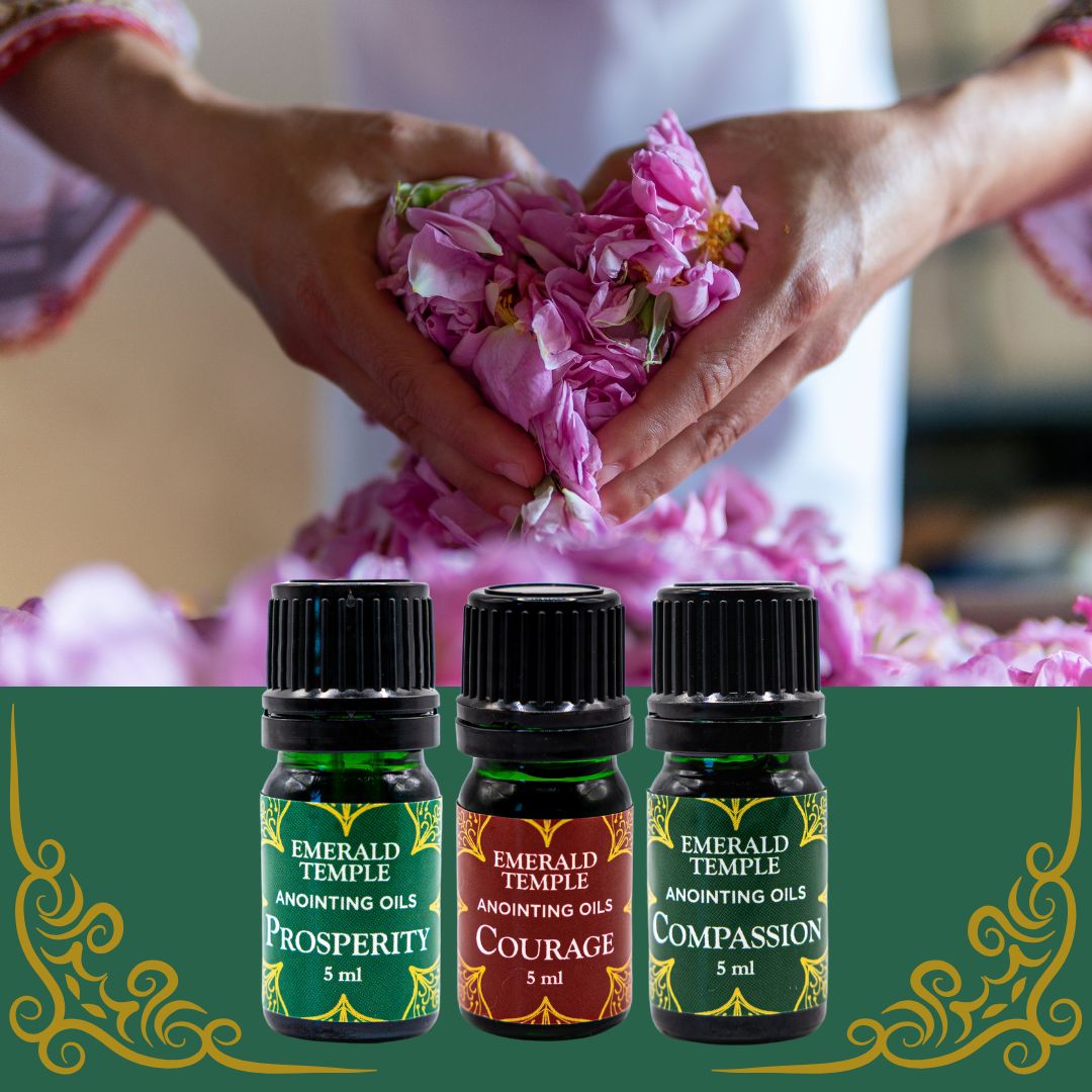 Three bottles of Emerald Temple anointing oils, each labeled with different attributes such as Prosperity, Courage, and Compassion, surrounded by a backdrop of flowers.
