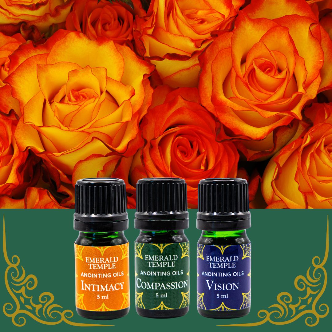 Three bottles of Emerald Temple anointing oils, labeled Intimacy, Compassion, and Vision, arranged against a background of orange roses.
